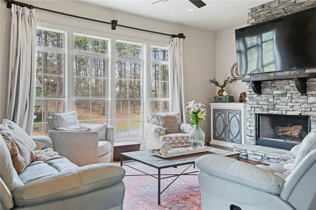 Natural light floods this inviting living room, centered around a striking stone fireplace.