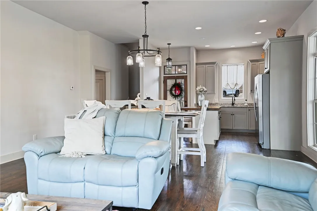 Rich hardwood flooring stretches across an open-concept layout, connecting the inviting living area to a well-appointed kitchen.