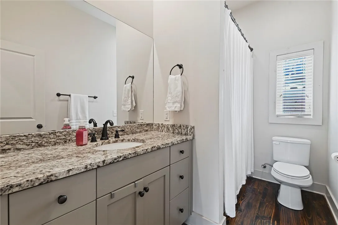 A well-appointed bathroom with a granite vanity and richly toned hardwood flooring.