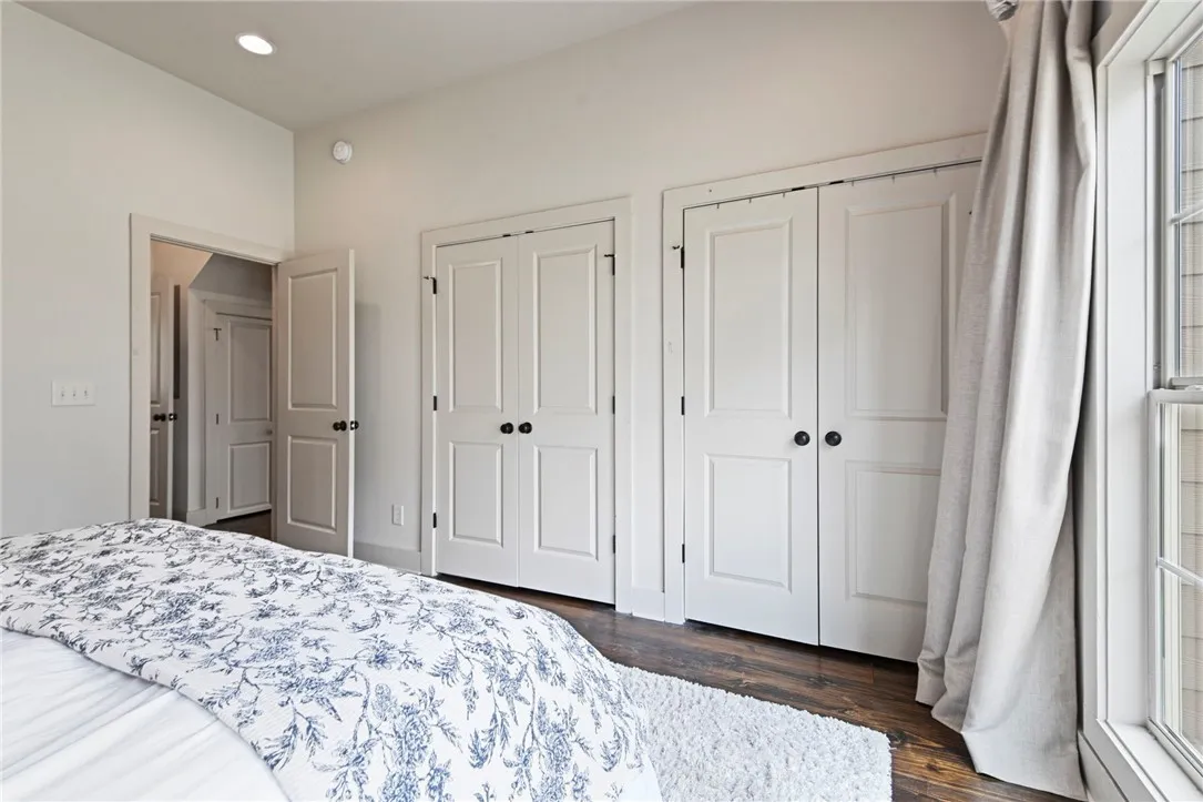 Hardwood flooring extends throughout this well-lit bedroom, offering ample closet space and natural light.