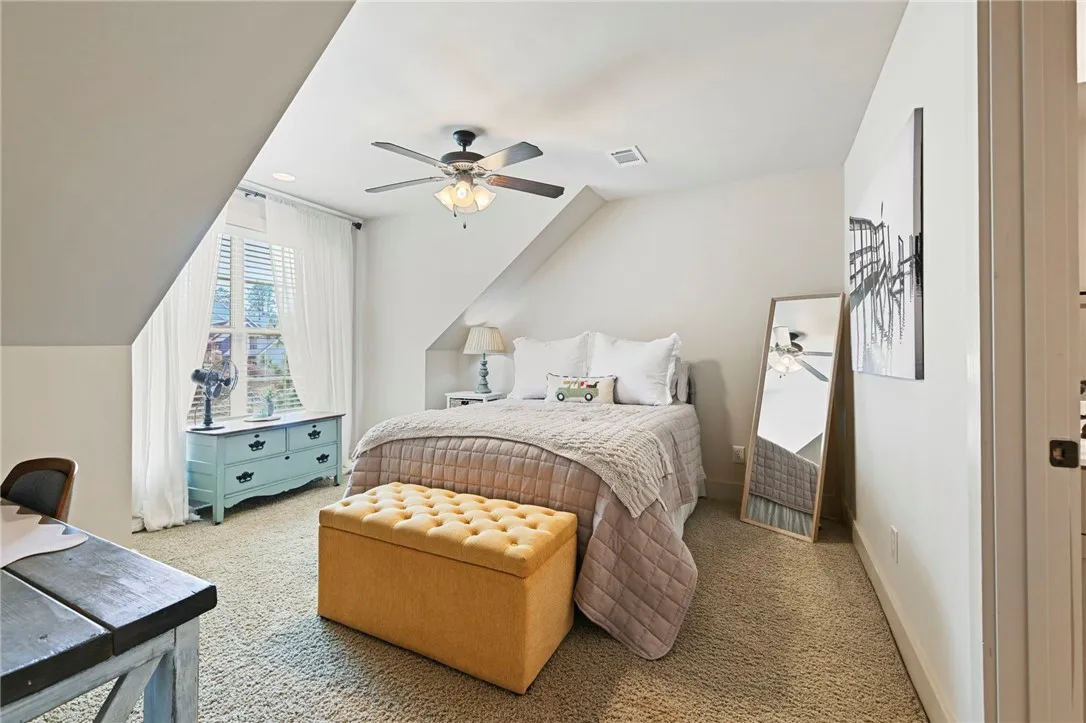 A cozy bedroom with a sloped ceiling and a window providing natural illumination.