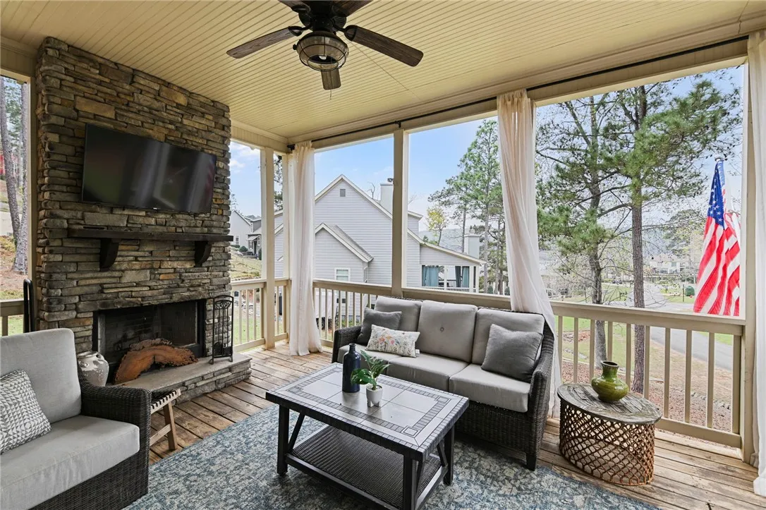 An inviting screened porch featuring a cozy stone fireplace, perfect for outdoor relaxation.