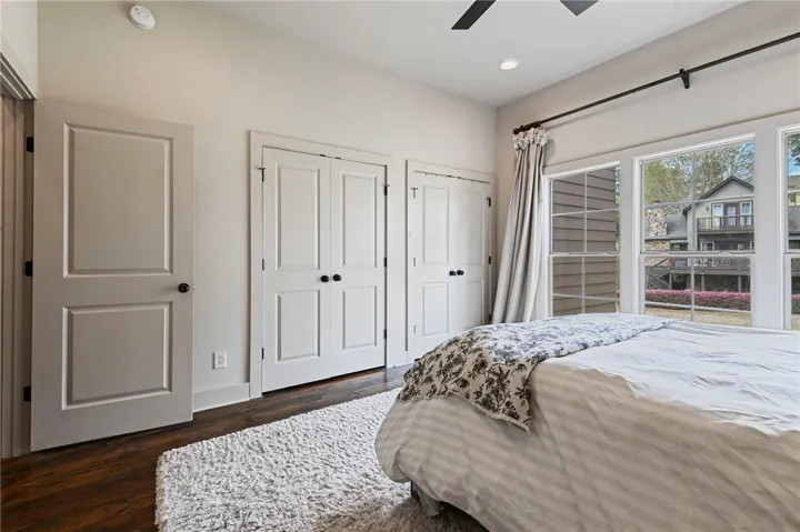 Wood flooring and large windows create a well-lit and comfortable bedroom retreat.