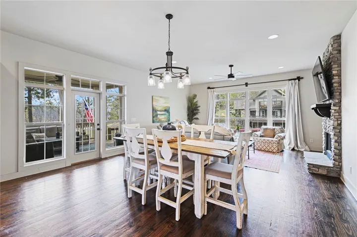 Hardwood floors stretch across this open-concept space, complemented by a stone fireplace and expansive windows.