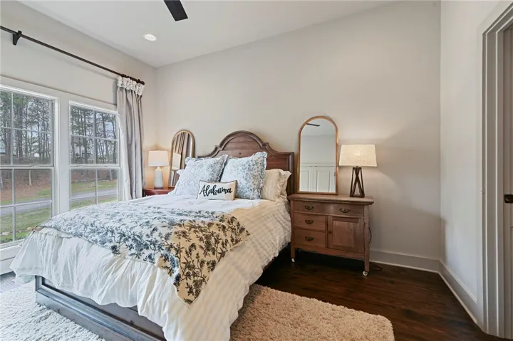 Natural light floods this charming bedroom featuring polished hardwood flooring and serene views.