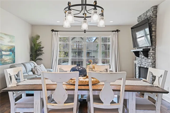 A charming dining space with a stone fireplace and abundant natural light from large windows.