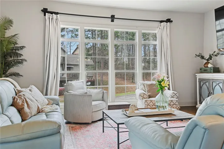 A wall of windows overlooks tranquil greenery, bathing this inviting living space in natural illumination.