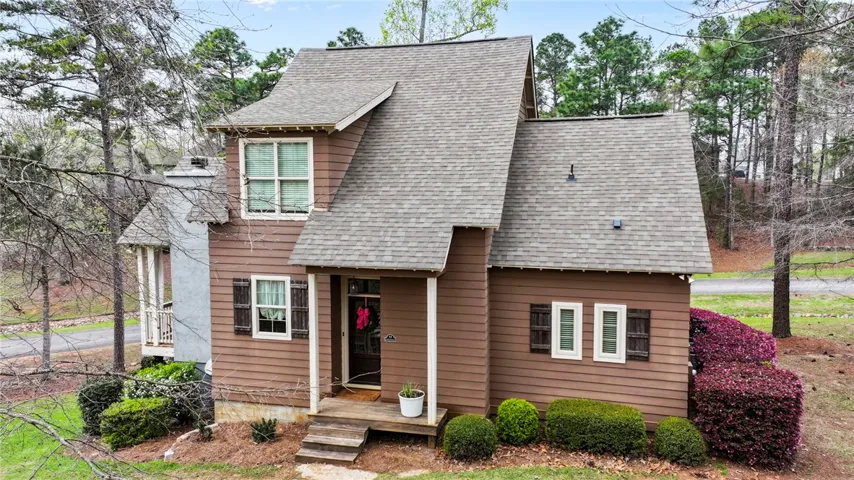 A charming exterior with brown siding and a gabled roof, nestled among mature trees.