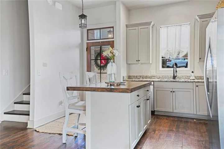 A compact kitchen island, warm wood flooring, and light cabinetry define this inviting culinary space.