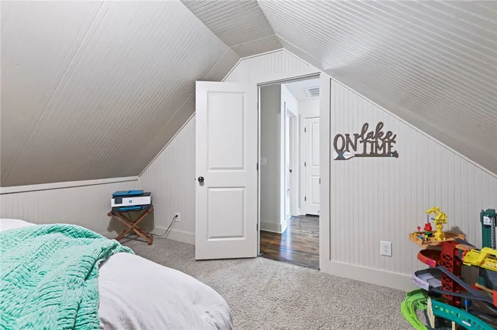 A naturally illuminated bedroom offers cozy comfort with carpet flooring and sloped ceilings.