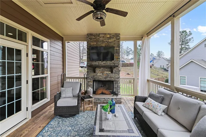 An inviting screened porch with a stone fireplace offers a cozy outdoor living space.