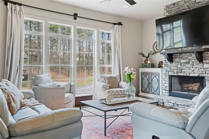 Natural light floods this inviting living room, centered around a striking stone fireplace.