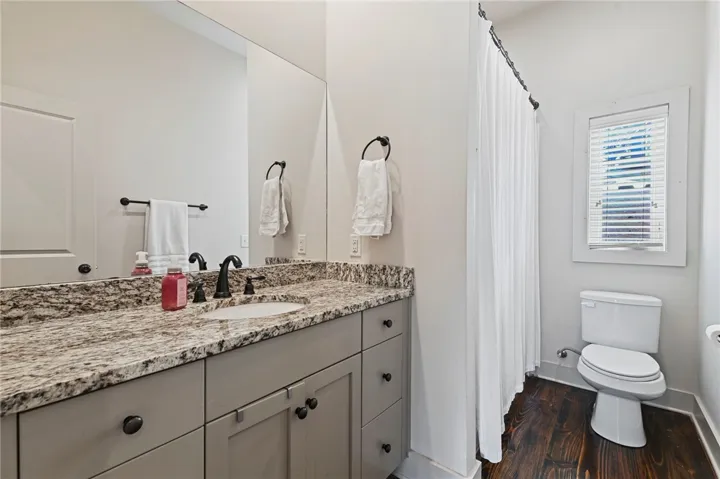 A well-appointed bathroom with a granite vanity and richly toned hardwood flooring.