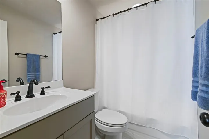A well-appointed bathroom features a modern vanity with a dark faucet, contrasting against the clean white shower curtain and light-colored walls.