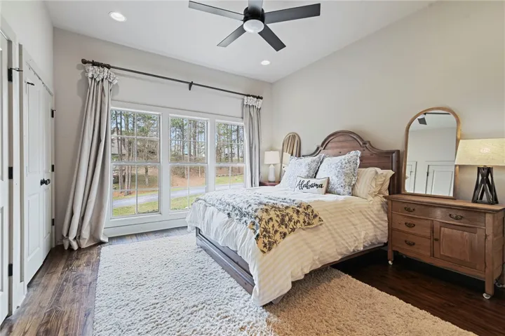 A tranquil sleeping space offers beautiful hardwood flooring and large windows, bathing the room in natural light.