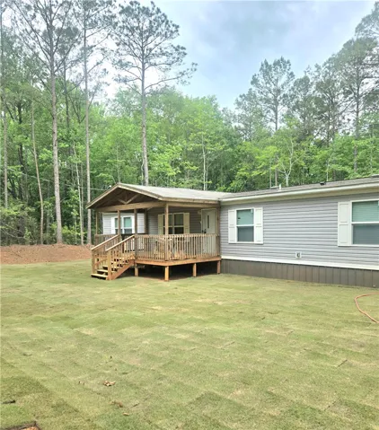 This charming home offers a welcoming porch, perfect for enjoying the serene wooded surroundings.