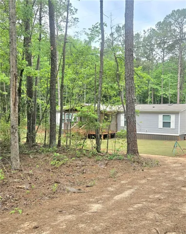 This peaceful property offers a serene retreat surrounded by lush greenery. View from the road/driveway.