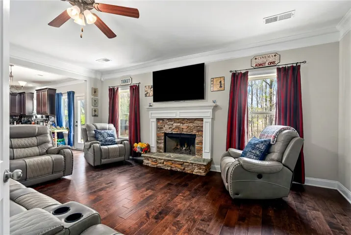 Large living room with wood floors, stacked stone fireplace.