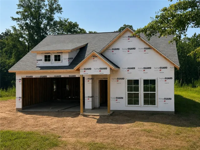 A newly framed residence, sheathed in protective wrap, awaits its final exterior finishes.