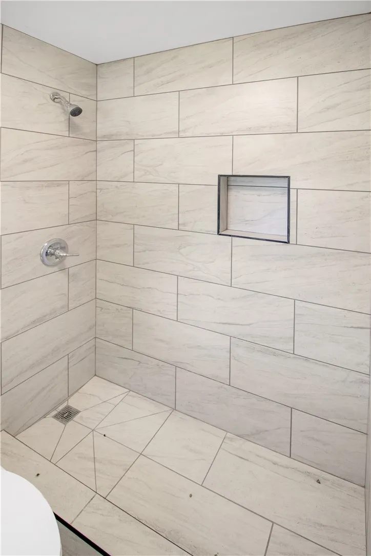 Step into this contemporary shower featuring sleek tiled walls and a convenient recessed niche.