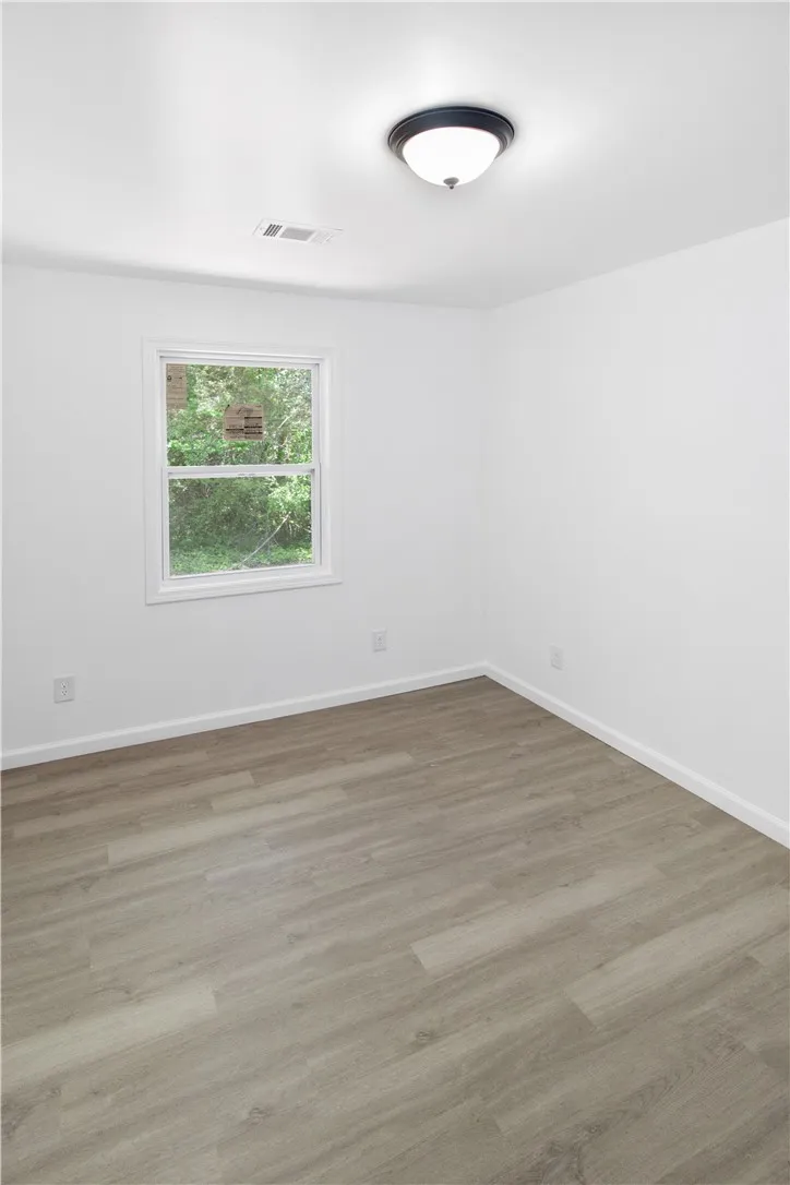 Bright and airy room with durable flooring and ample natural light through a classic window.