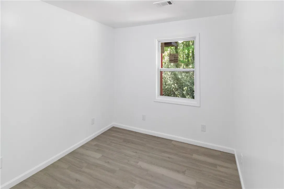 This bright bedroom features durable flooring and a window with lush outdoor views.