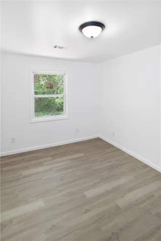 Bright and airy room with durable flooring and ample natural light through a classic window.