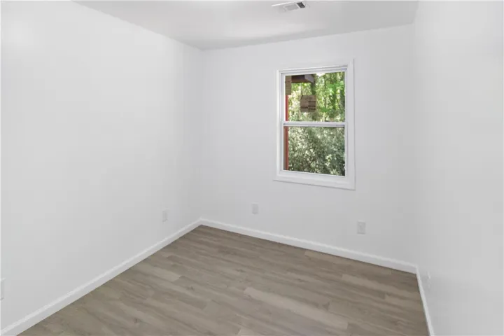This bright bedroom features durable flooring and a window with lush outdoor views.