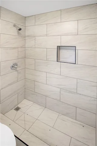 Step into this contemporary shower featuring sleek tiled walls and a convenient recessed niche.