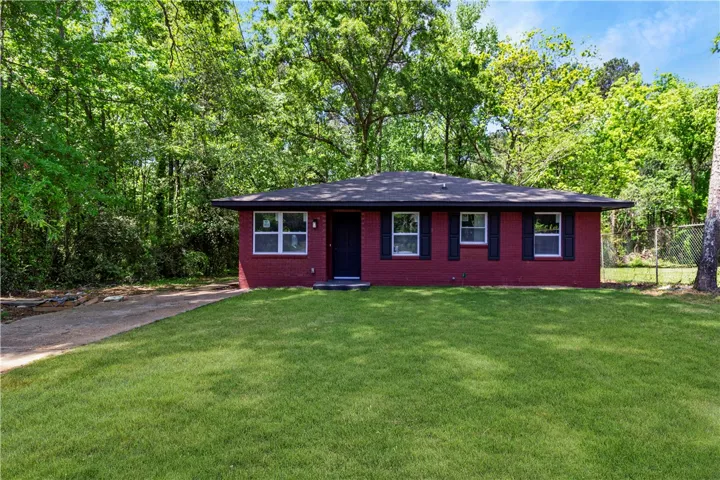 Charming single-story residence with a vibrant exterior, nestled amongst lush greenery.