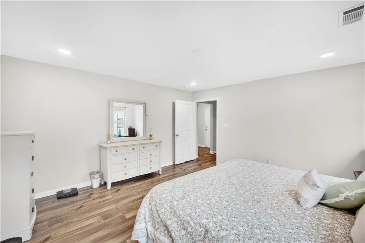 Well-lit sleeping quarters with rich wood-style flooring and a clean, neutral palette.