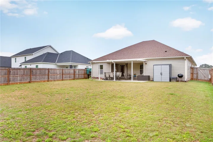 A spacious, fenced backyard offers a concrete patio with an awning, perfect for outdoor entertaining.