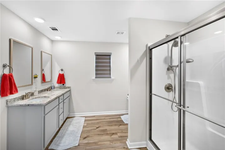 A well-appointed bathroom features a double vanity with granite counters and a glass-enclosed shower.
