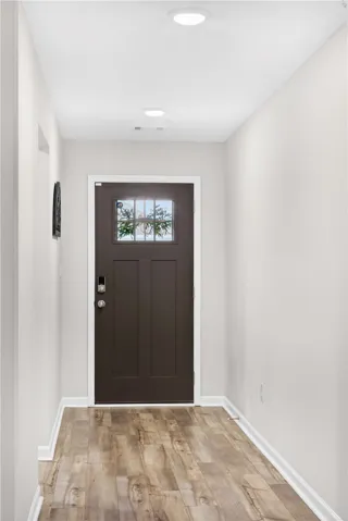 A welcoming entry hall with durable LVP flooring and a rich, dark paneled door.