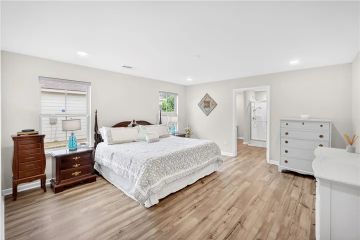 Natural light illuminates the wide-plank flooring of this serene primary bedroom.