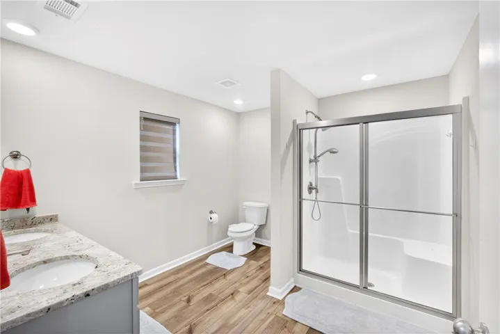 A well-appointed bath features a double vanity and a glass-enclosed shower with contemporary fixtures.