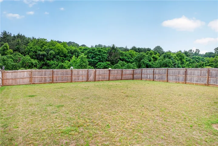 A spacious backyard with mature trees providing a lush backdrop.