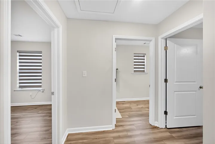 Streamlined LVP flooring flows through this bright, naturally lit hallway connecting rooms.