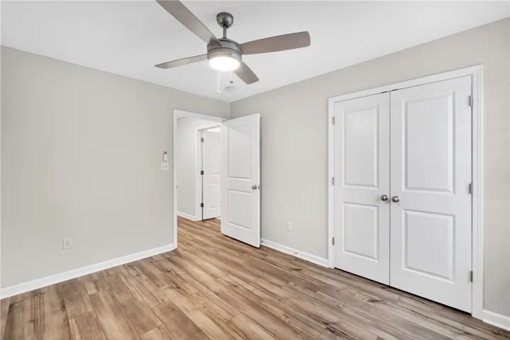 A quiet bedroom showcases light-colored laminate flooring and a modern ceiling fan for comfort.