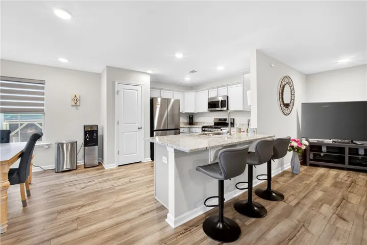 Granite counters and stainless steel appliances outfit this open-concept kitchen, flowing into a welcoming living space.