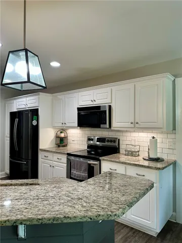 Contemporary kitchen features elegant granite countertops, classic white cabinetry, and modern appliances.