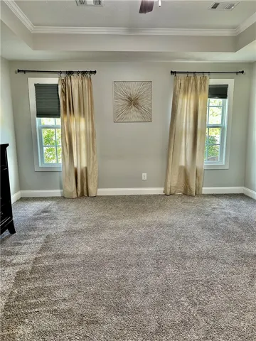 This spacious primary bedroom offers ample natural light and plush carpet.