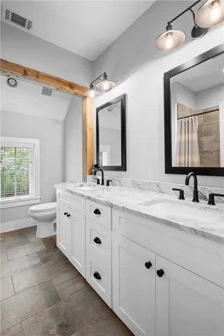 A spacious second-floor bath serves two bedrooms and features a dual-sink vanity, jetted tub with tile surround, and warm wood accents.