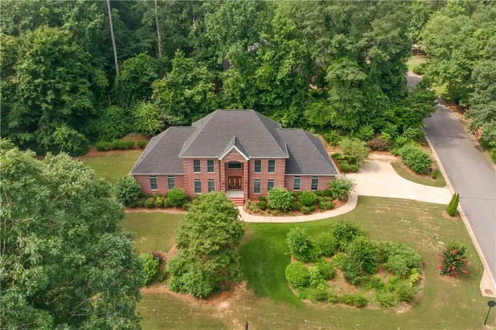 Mature trees and lush landscaping frame this grand brick residence, offering privacy and curb appeal.