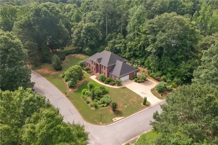 An aerial perspective reveals this brick residence nestled within a mature, verdant landscape.