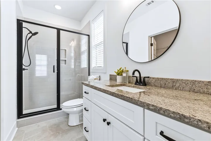Quite nice ensuite with striking, step in tile shower, black delta fixtures & large vanity.