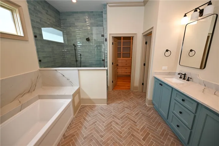 Huge primary bathroom with a garden tub, and a beautiful blue tiled shower.