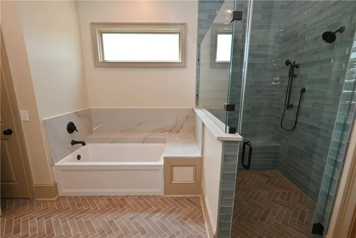 Tile and frameless glass shower with bench and dual showerheads.