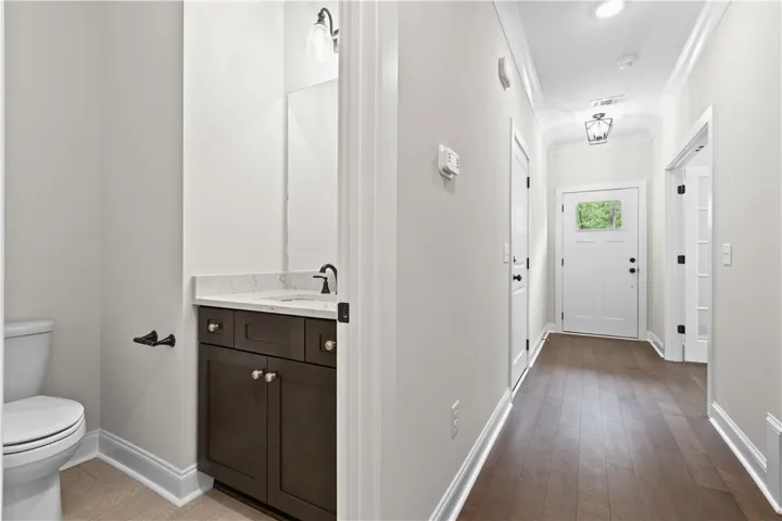Facing the front door entrance is this bright hallway, which shows the half bath and rich hardwood floors downstairs.