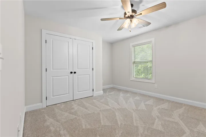 This spacious bedroom offers comfortable carpeting and a bright window, creating a serene view.